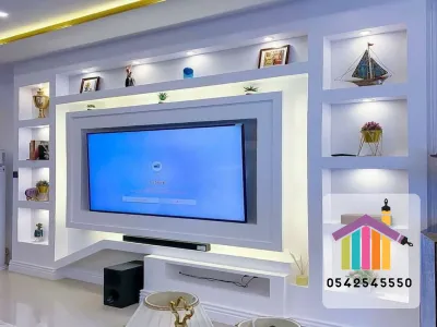 بانوهات أنيقة مع إنارة مخفية تمنح عمقًا بصريًا وتوزيعًا مريحًا للضوء. كلمات دلالية: بانوهات, إضاءة مخفية, ديكور تلفاز, خلفية شاشة, حائط مميز